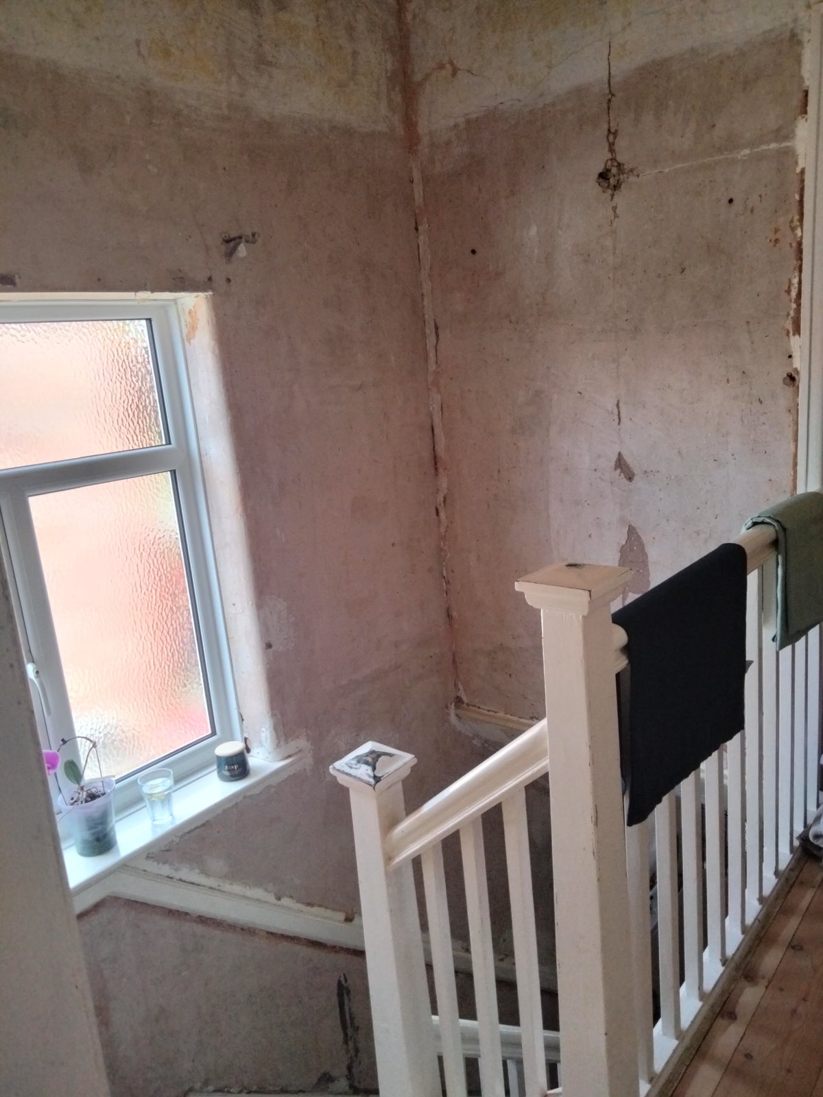 The landing side of a stairwell, plastered smooth above the banister
