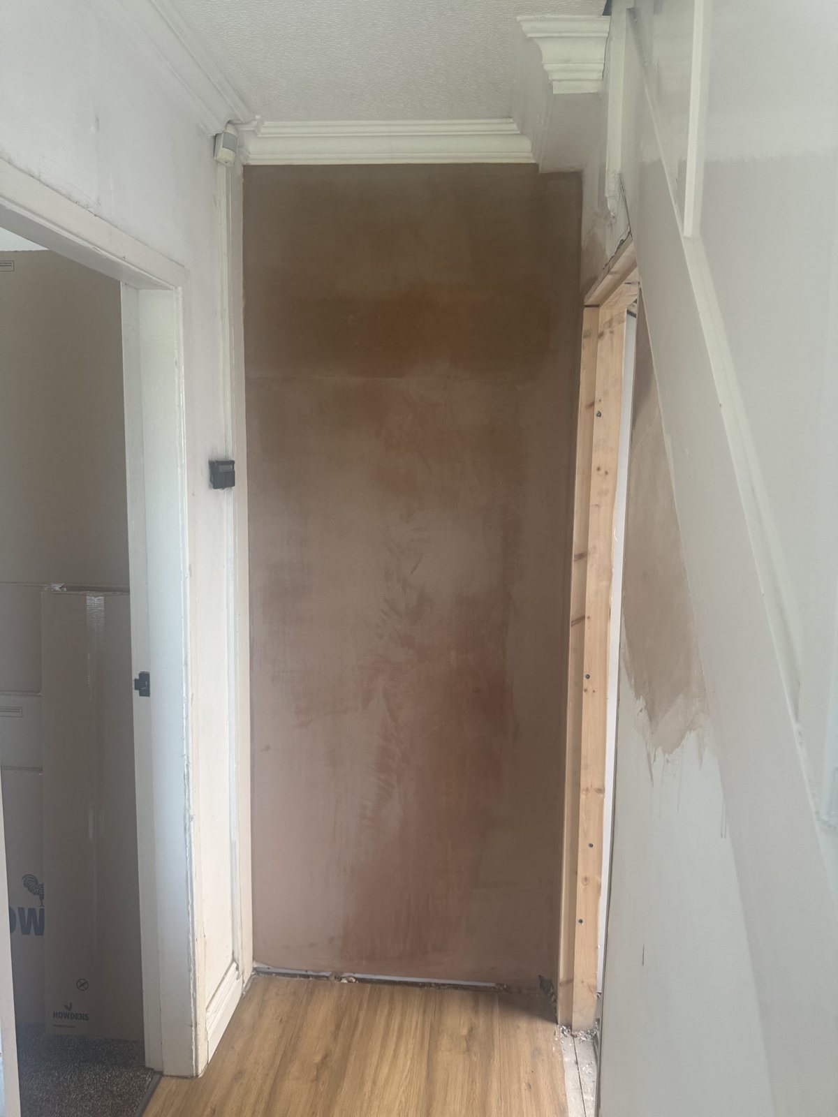 A hallway chimney breast freshly plastered between white painted woodwork