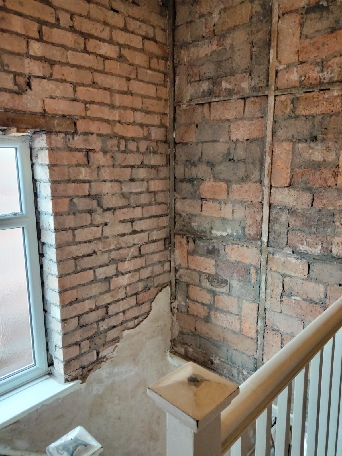 Before: a stairwell stripped back to bare brick around its window